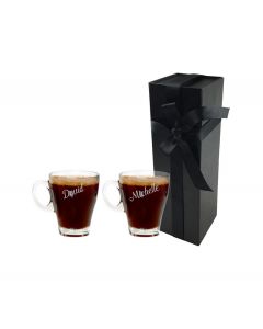 Personalised glass cup that can be used for any hot drink. Engraved with any names and initials, this picture shows two cups standing in front of a tall and thin black box with a white background