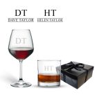tumbler glass and wine glass both engraved with any name and initial, positioned in front of a black gift box with a satin bow